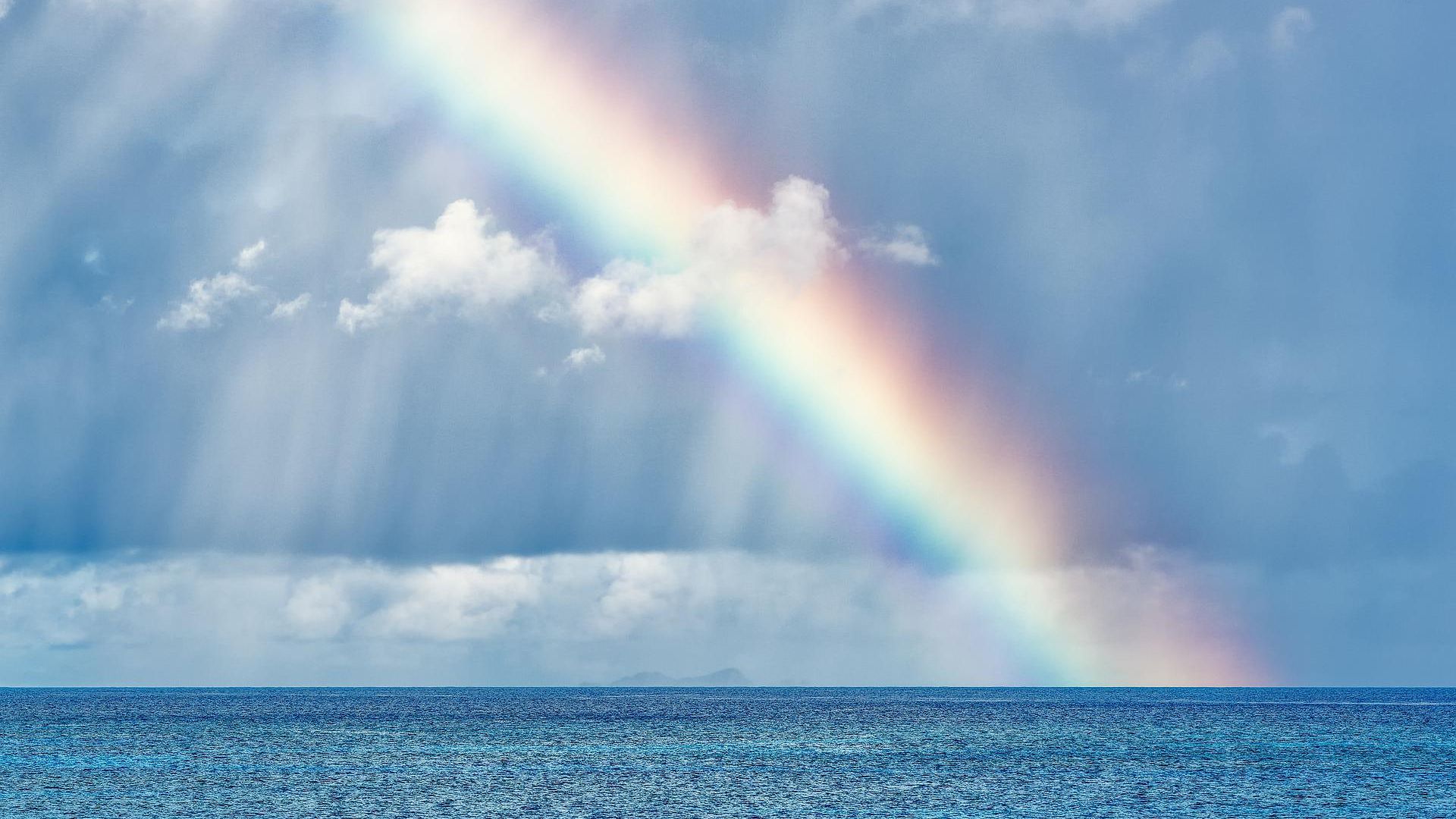 Regenbogen über dem Meer, Wolken und Regen